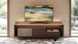 La madia Freeda di Giessegi interpreta il living contemporaneo attraverso un equilibrio tra matericità e leggerezza visiva. La struttura e i bussolotti in nobilitato effetto legno Teak dialogano con il top con alzatina laccata Papiro perlato, creando un elegante contrasto tra superfici calde e luminose. L’anta in vetro bronzo satinato, incorniciata dal telaio in alluminio Champagne, introduce una nota scenografica ripresa nei piedini coordinati. Misure: L 207 × P 58,3 × H 73,8 cm. Prezzo: a partire da 1.388 euro IVA esclusa. www.giessegi.it