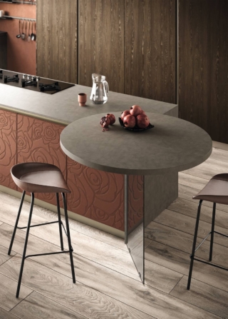 Nella cucina Mirage 4 di Moretti Compact, la texture Rose sul colore Malta Marrone delle ante dell'isola è abbinata alla finitura calda del melaminico Rovere Fiammato di basi e colonne. I piani sono in laminato HPL colore zinco. Sembra sospeso il piano snack con la gamba in vetro trasparente fumé.
Una base decorata con Rose da 60 cm, esclusi top, gola o maniglia e zoccolo costa 350 euro. www.moretticompact.it