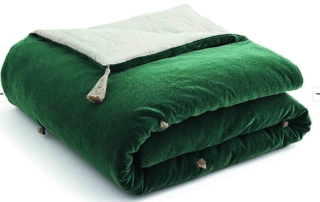 Double face, la trapunta Nidhi di La Redoute è in velluto di cotone verde e lino beige, impreziosita da quattro nappine negli angoli. L'imbottitura è 100% poliestere. Misura 130 x 180 cm.  www.laredoute.com