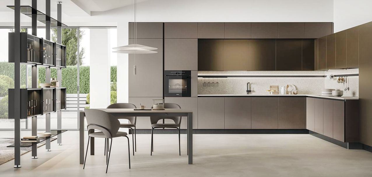 Fa parte della collezione Aliant di Stosa la grande cucina angolare caratterizzata da colori e finiture raffinate: le ante delle basi e delle colonne in vetro opaco Terra e quelle dei pensili in Pet opaco Copper Brown. La pratica barra continua Sign, fissata allo schienale in Neolith Retrostone, è accessoriata con portabicchieri, portarotolo, ganci portaoggetti e illuminazione integrata. La scenografica libreria Vertical Line, con la struttura in metallo e le mensole in vetro fumé, mette in collegamento la zona operativa con il living. Prezzo su richiesta. https://www.stosacucine.com