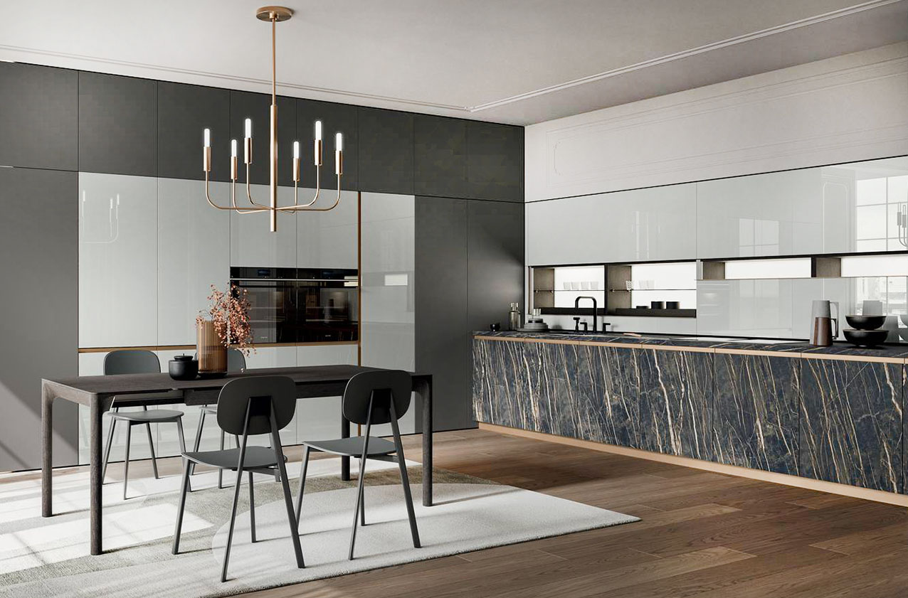 Finiture luxury per l'ampia cucina Fusion di Arredo3 che “veste” l'angolo con le ante delle basi in Laminam Noir Desir effetto marmo, i pensili e le colonne in vetro lucido piuma messi in risalto dalle ante dei moduli in laccato opaco vulcano. Al centro della composizione trova posto un grande tavolo rettangolare nella finitura legno scuro. Prezzo su richiesta. https://www.arredo3.com
