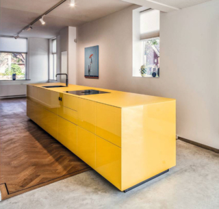 Scenografica e decorativa l'ampia isola Artematica di Valcucine che  è realizzata in vetro  lucido e opaco Giallo Zafferano che la trasforma in una sorta di scultura monolitica in grado di dialogare con l'ambiente grazie alle superfici riflettenti. Prezzo su richiesta. https://www.valcucine.com
