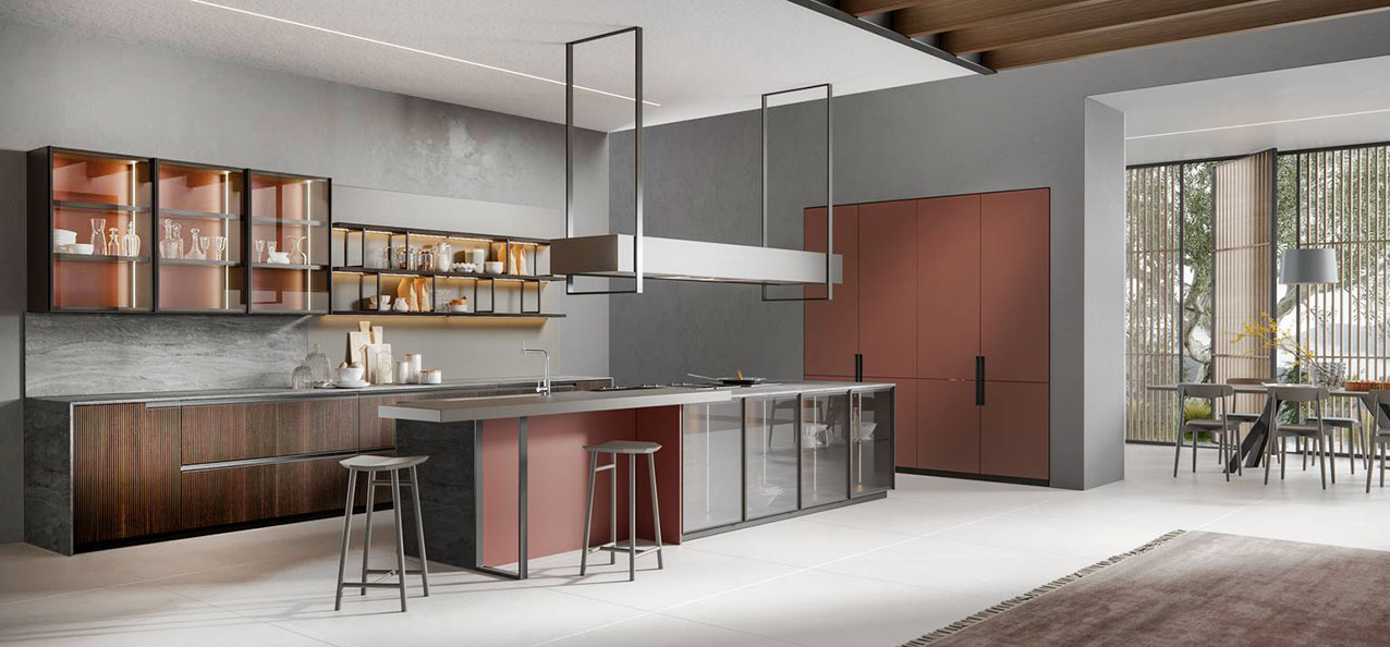 La grande isola attrezzata nella cucina industrial E03 di Scandola Mobili ha le ante in laccato opaco Rosso Granata, coordinate con quelle dell'armadiatura a parete, e una serie di moduli/vetrina che permettono di esporre stoviglie e oggetti. Le basi a parete hanno i frontali cannettati in legno di rovere. Un modulo base da 60 cm con un'anta, prezzo 560 euro + IVA. https://scandolamobili.it