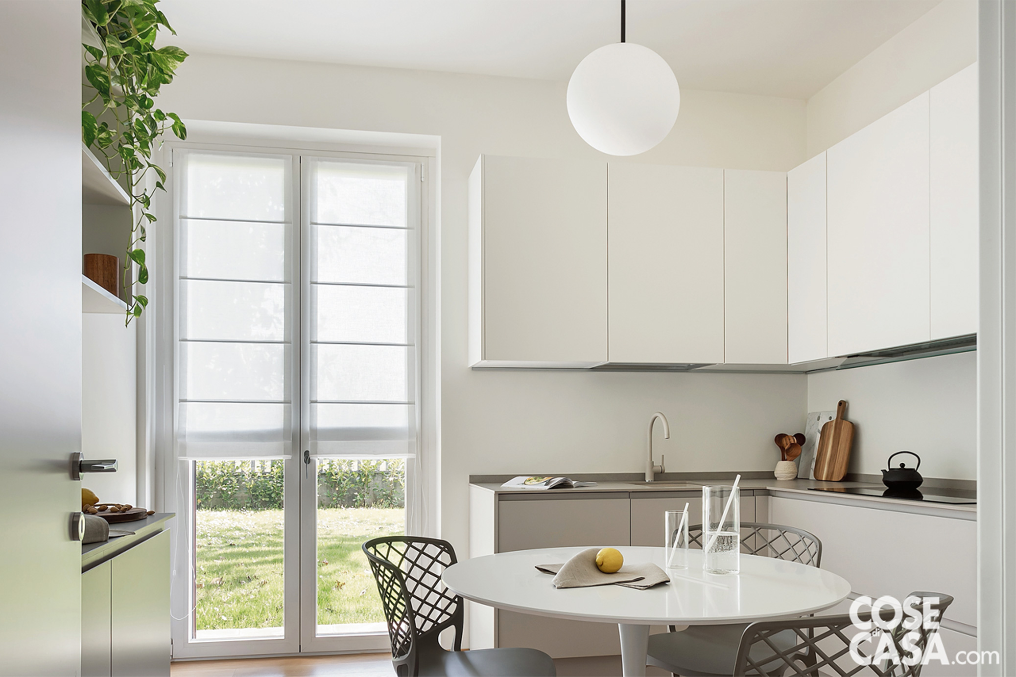 Cucina con tavolo rotondo, sedie e lampada sferica a sospensione Cucina con tavolo rotondo, sedie e lampada sferica a sospensione