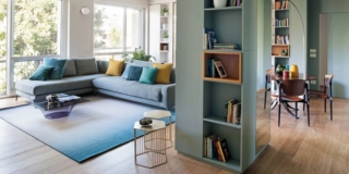 Zona living con divano angolare, tavolo rotondo e sedie