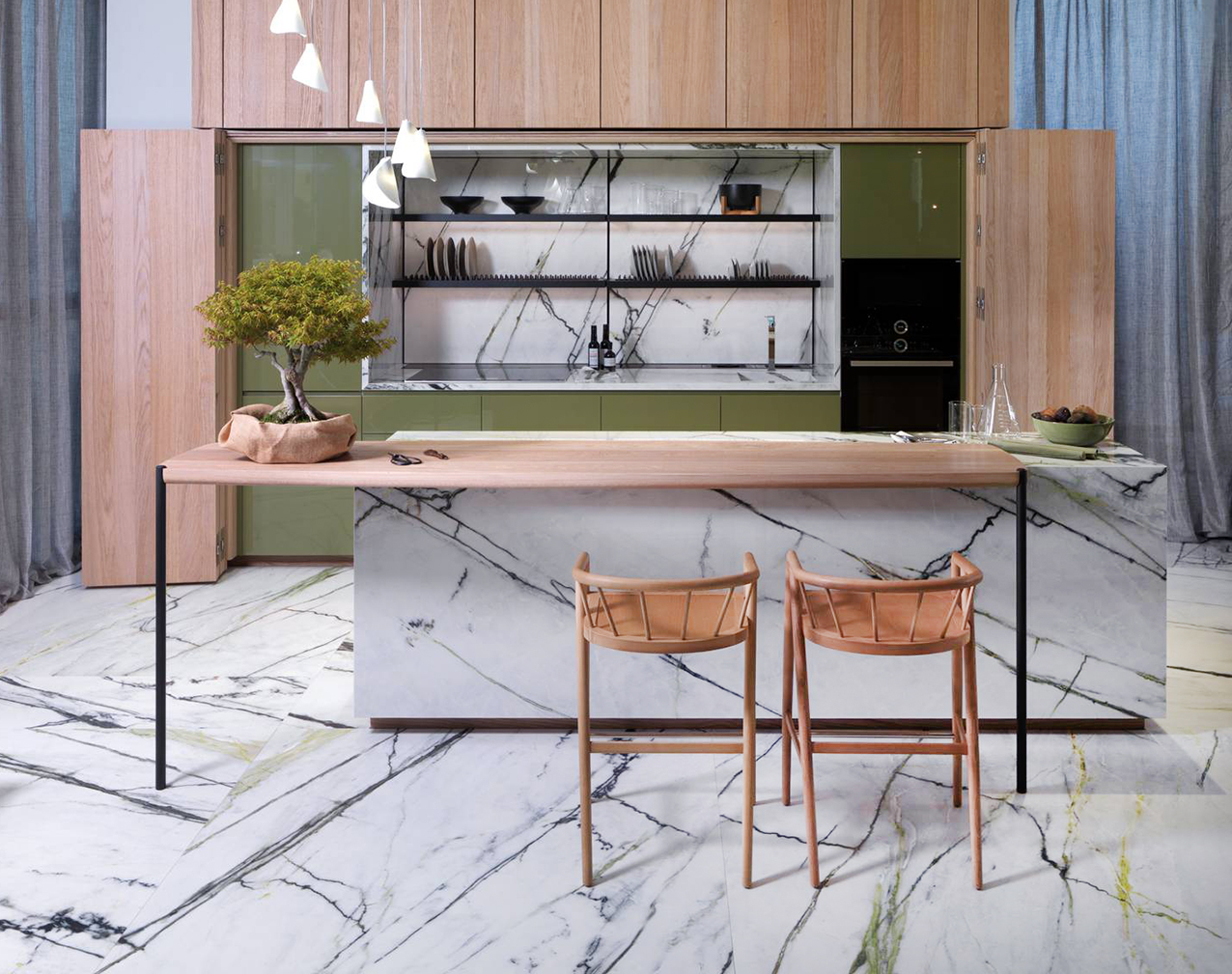 Nella cucina Buffet Forest E7.90 · E5.90 di Porcelanosa sono presenti la zona operativa, che può essere nascosta dalle ante con impiallacciatura di rovere puro del sistema Forest quando non serve, e da un'isola, con bancone snack, nella finitura Xtone Calacata Green levigato come il piano di lavoro e lo schienale. Le ante lisce delle basi e dei pensili sono realizzate in laccato Orégano lucido.  Prezzo su richiesta. https://www.porcelanosa.com