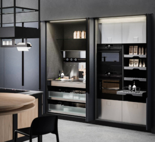 CUCINAnD'O di Aran Cucine si sviluppa intorno all'isola centrale con il piano snack rotondo in legno di olmo ed è caratterizzata da una linea minimal e da una struttura in laccato grigio opaco; il piano di lavoro è realizzato in acciaio inox. Il sistema ad ante a scomparsa, che si espande lungo tutta la parete della cucina, ne sottolinea l'estrema essenzialità e rivela scomparti e nicchie organizzate e attrezzate con piani estraibili, cassetti ed elettrodomestici ad incasso. Prezzo su richiesta. https://www.arancucine.it