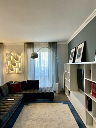 Tappeto grande e chiaro, con bordo perimetrale blu scuro, che riempie tutto lo spazio tra divano e TV Tappeto grande e chiaro, con bordo perimetrale blu scuro, che riempie tutto lo spazio tra divano e TV