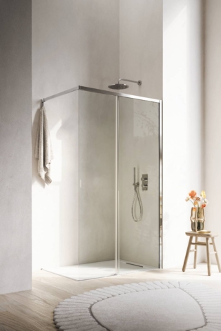 Box doccia SIPARIO della linea Ibra Showers con configurazione walk-in con anta scorrevole in vetro trasparente da 6 mm affiancata a un vetro fisso da 8 mm. Profili e traversa di sostegno in alluminio con porta accappatoio integrato Brill; presa maniglia ricavata direttamente sull’anta. In abbinamento, piatto doccia Mark in Tekno Gelcoat Bianco L 100 x P 70 cm.
