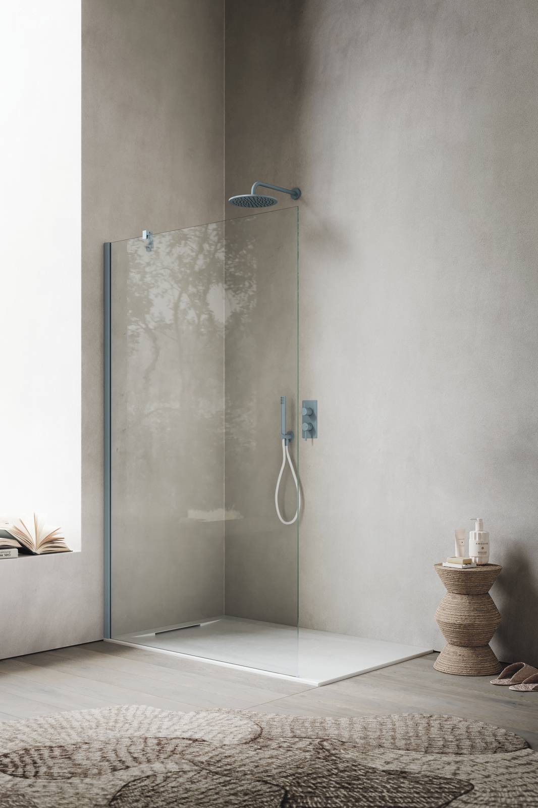 Box doccia UNIKO della linea Ibra Showers con configurazione walk-in vetro trasparente da 8 mm; profilo e sostegno muro-vetro inclinato in finitura Ceruleo. In abbinamento, piatto doccia Mark in Tekno Gelcoat Bianco L 120 x P 80 cm.