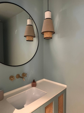 Siamo in una powdwer room con lavabo e wc: il colore scelto per ottenere l’effetto scatola è un azzurro polveroso, neutro ma con un suo carattere ben preciso, interrotto solo dalle ante in paglia di Vienna del mobile,  riprese nei dettagli della luce a sospensione. Il risultato? Soft ed elegante, sobrio ma non noioso.  La scelta della rubinetteria in ottone satinato aggiunge una cura per il dettaglio che lo rende ancora più chic.