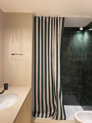 Una tenda a righe bianche e blu, che si abbina alle piastrelle rettangolari e lievemente mosse, sempre nei toni del blu: ecco un bagno con una nota allegra, in cui la tenda diventa il focus dello stile.