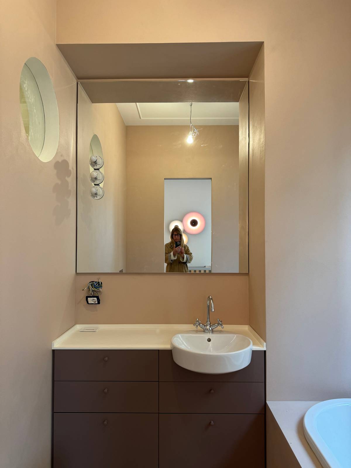 Siamo in un bagno ancora in work in progress, che sta per essere ultimato: in questo caso la scelta del modello del lavandino semincasso ha una forma tondeggiante. Il mobile rimane inserito nella nicchia: una soluzione che fa risparmiare ancora più spazio, mentre lo specchio a tutta parete amplifica l’ambiente.