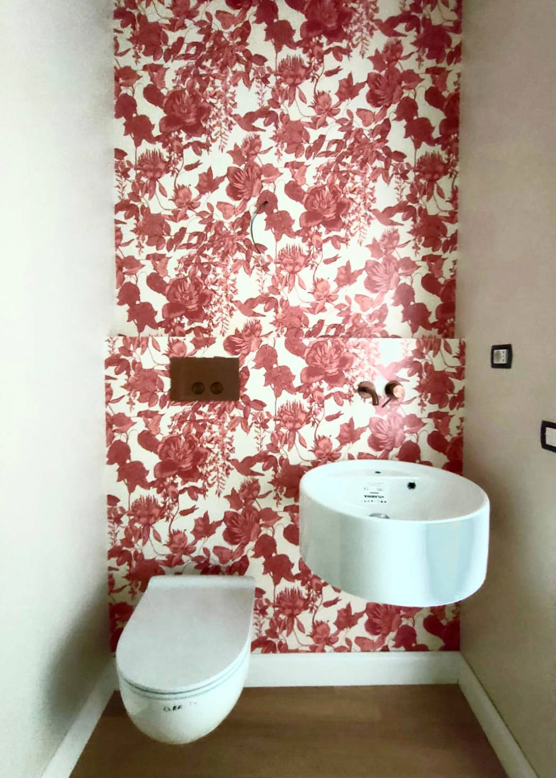 In questo bagnetto ospiti la parete con lavabo e WC è stata rivestita con una carta floreale bianca e rossa che si fa notare, soprattutto perché è l’unico elemento decorato. Basta lei per creare un effetto molto decorativo.