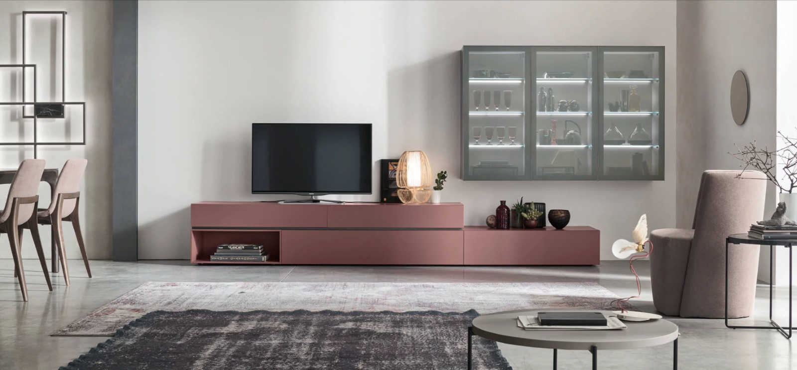 Unix SU2109 di Maronese è una composizione modulare pensata per organizzare la zona TV alternando contenitori e vani espositivi. La disposizione libera di moduli di diverse altezze e lunghezze consente di costruire configurazioni articolate e personalizzabili, mentre il separatore tra i contenitori può essere scelto in tinta o a contrasto. Nella composizione in foto la base è realizzata in laccato opaco Porpora, mentre la vetrinetta combina struttura in melaminico Grafite, telaio in alluminio Manganese e ante in vetro Trasparente Bronzo, creando un contrasto tra superfici opache, metallo e trasparenza. Misure L 369,6 x P 38,5/48,7 cm. Prezzo 5321,36 euro + iva. www.maronese.it